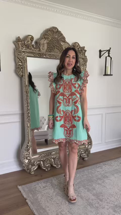 woman wearing a green short dress with a mirror in background