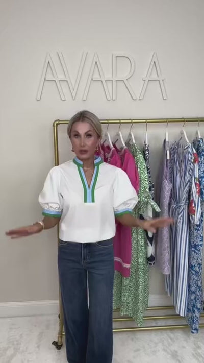 woman wearing a white adelaide top with a rack of clothing behind her