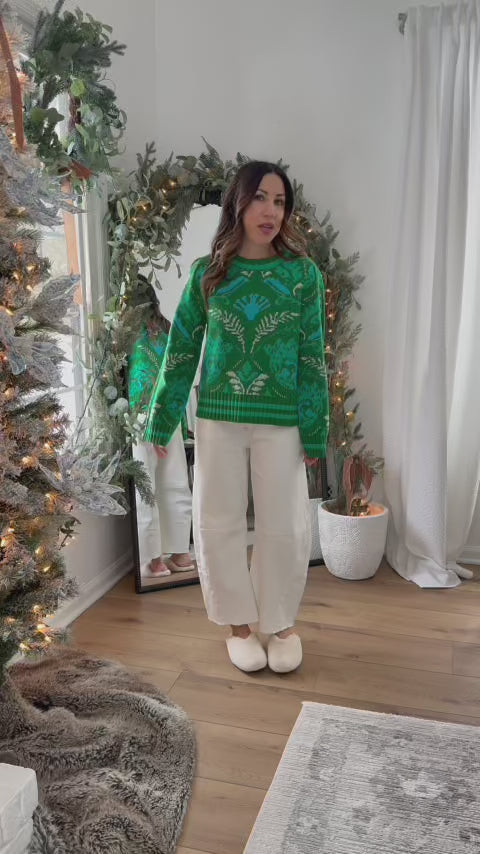 woman wearing a green fallon sweater with a mirror in the background
